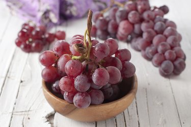 A small bunch of red grapes in a wooden dish