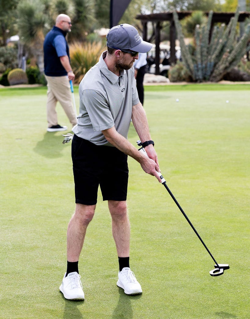 Golfer preparing to putt on a green with spectators in the background.