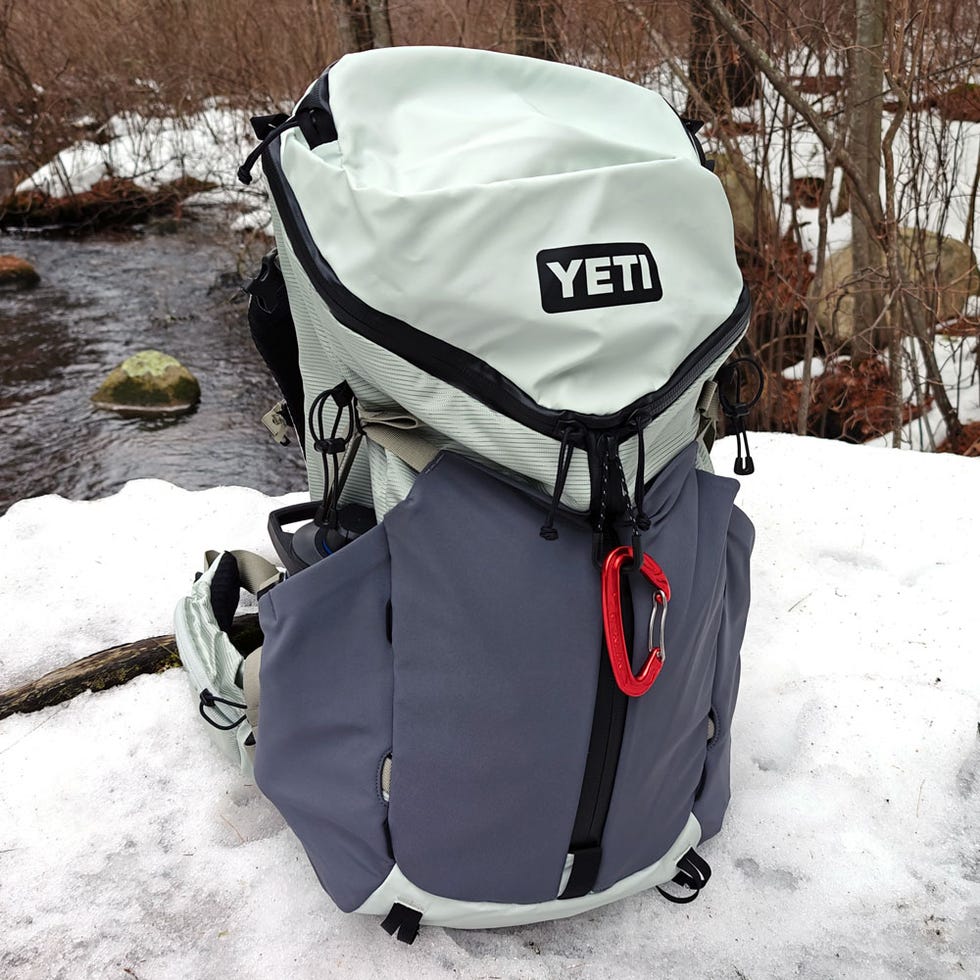 Yeti Skala 32L hiking backpack sitting in snow near an stream.