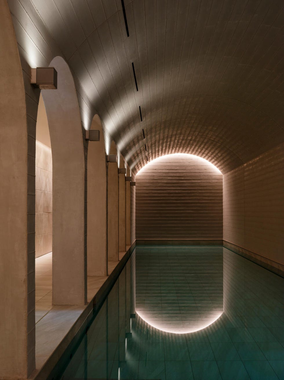 interior space featuring an illuminated swimming pool and architectural arches