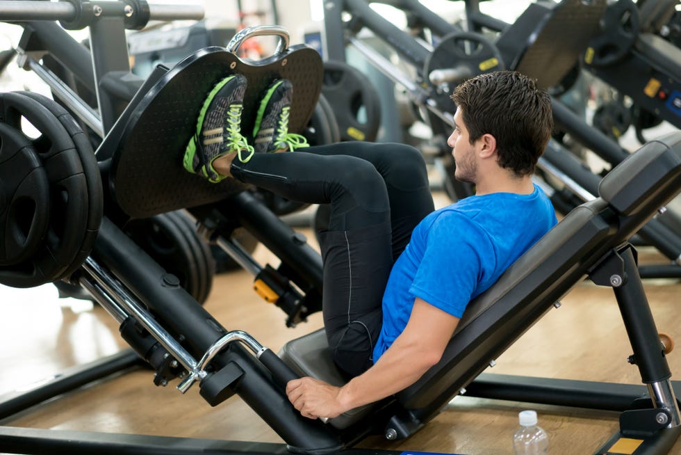 healthy man exercising at the gym on a leg press machine
