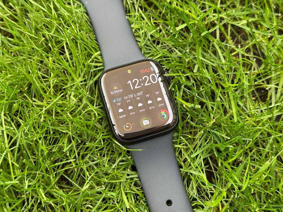 smartwatch displaying time and weather information resting on grass
