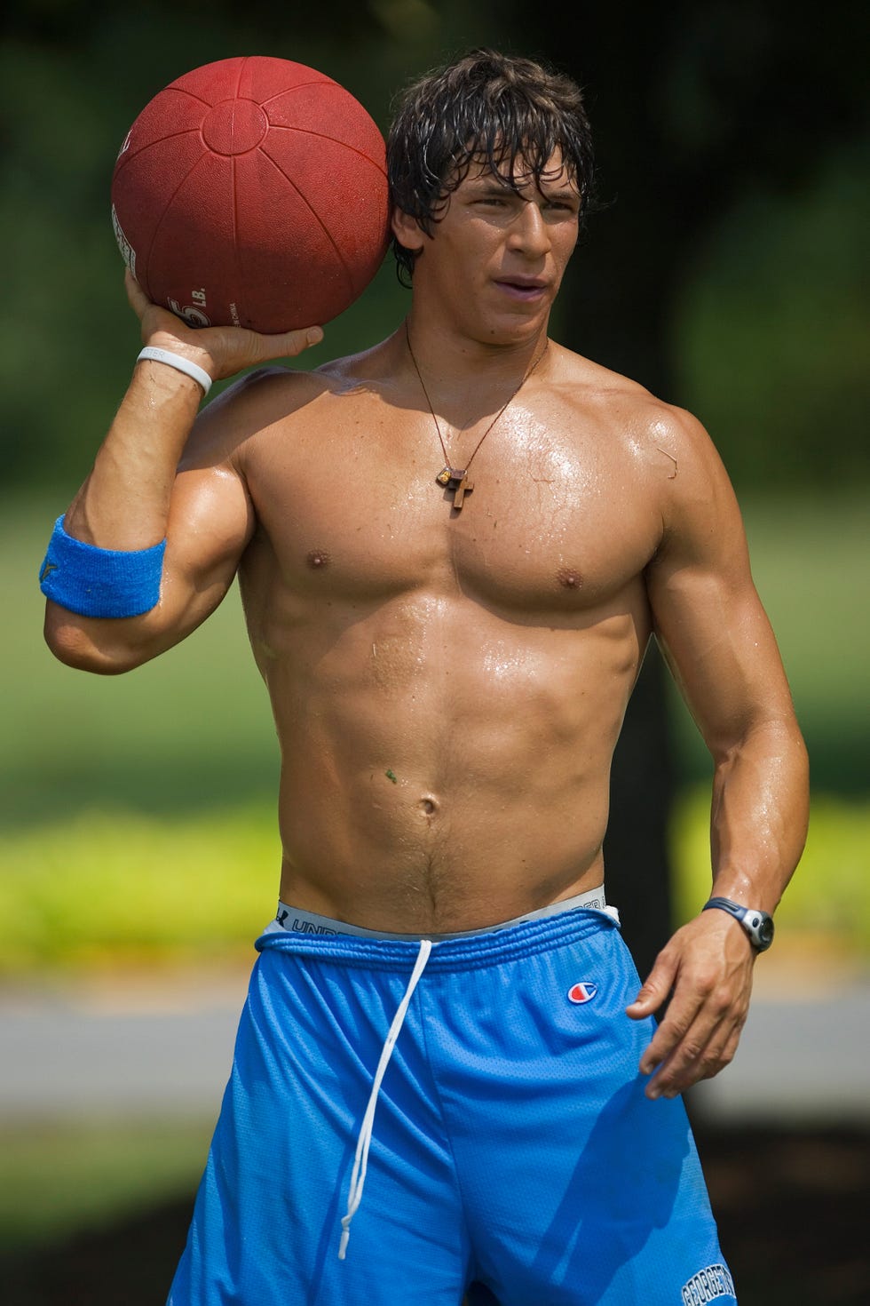 Male athlete preparing to throw a red football in an outdoor setting.