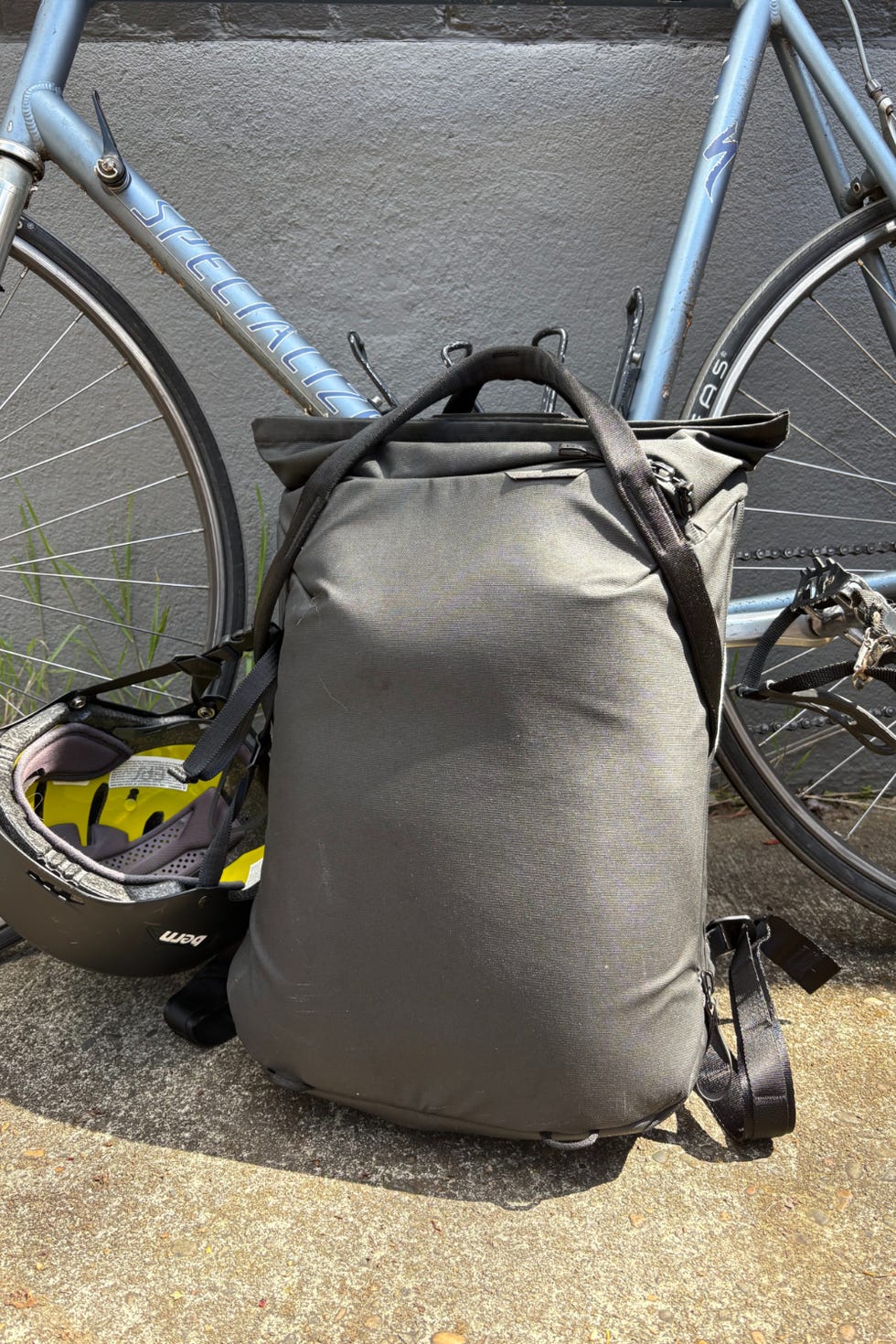 Backpack next to a bicycle on a concrete surface.