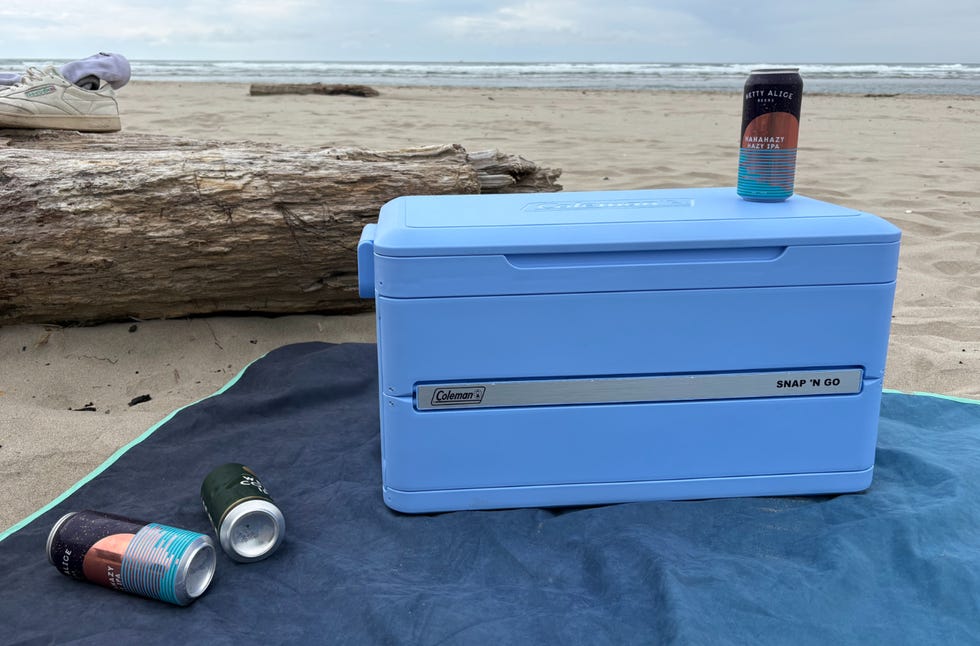 A cooler beside some drinks on a beach.
