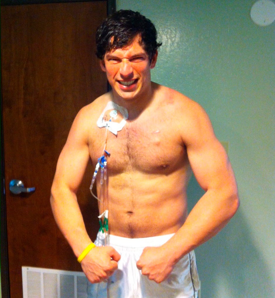 David with IV drip attached to his chest in a hospital-like setting.