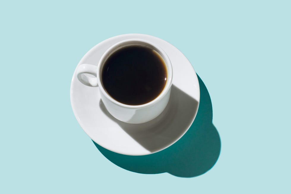 A coffee cup with dark coffee on a light blue background