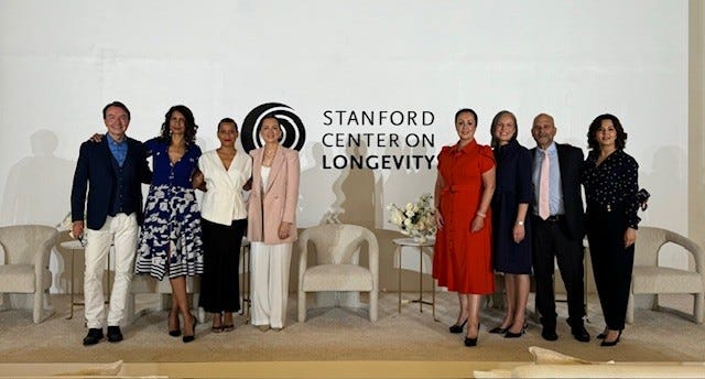 Group of individuals standing in front of a logo for the Stanford Center on Longevity.