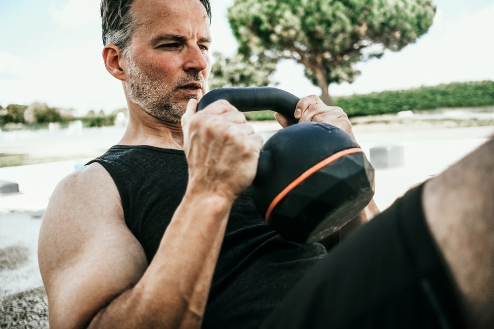 man doing kettlebell workout at outdoor gym