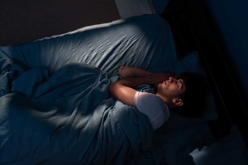 top view of young man sleeping on cozy bed in his bedroom