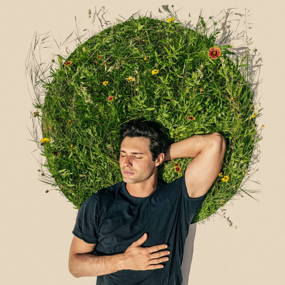 burnout. stress. stress relief, man laying on a circular patch of grass. stress free. reset. forest bathing. outdoors and mental health.