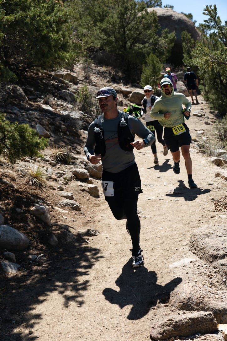 Trail runners on a rocky path surrounded by trees.