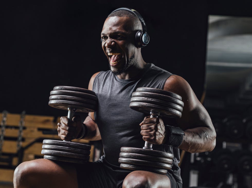 Athlete training with dumbbells in gym, screaming