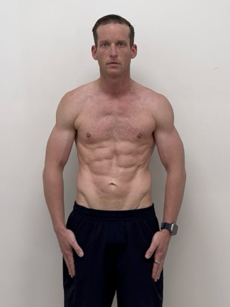 A fit man with a muscular physique standing bare-chested against a plain background.
