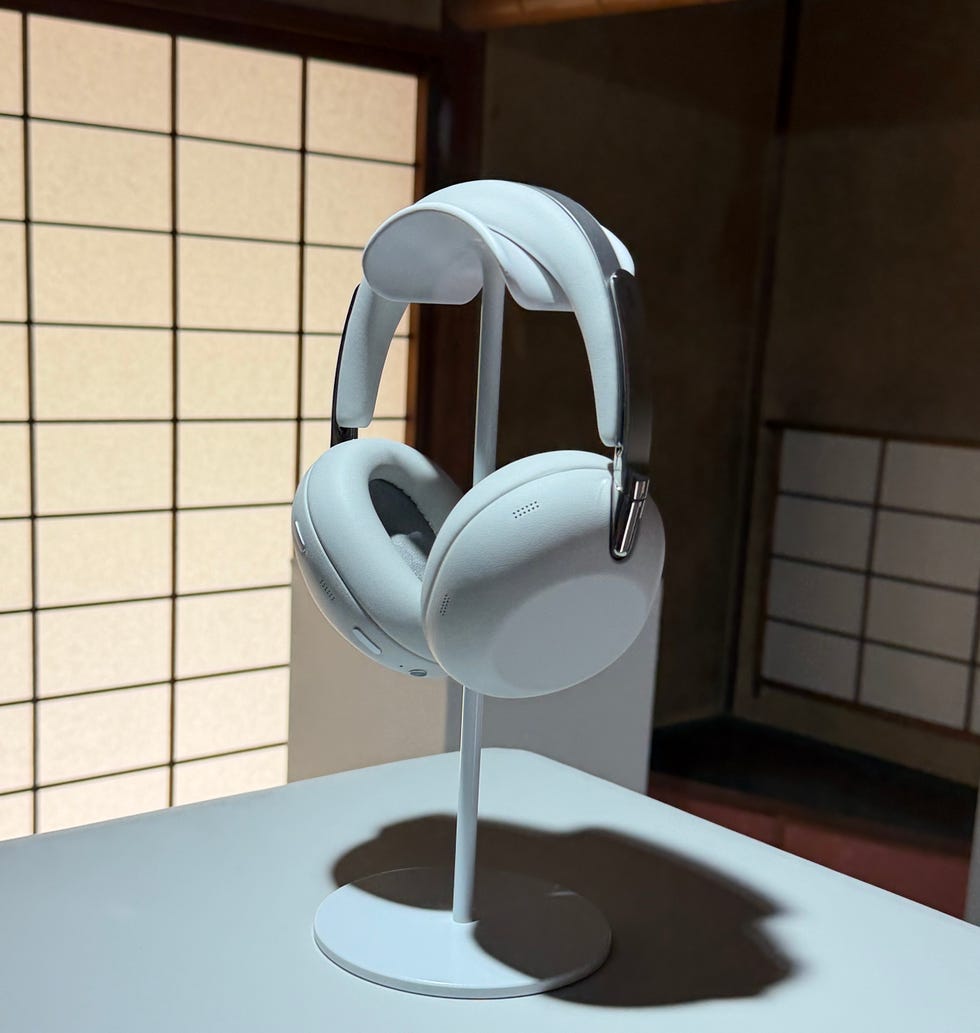 White over-ear headphones displayed on a stand against a muted background.