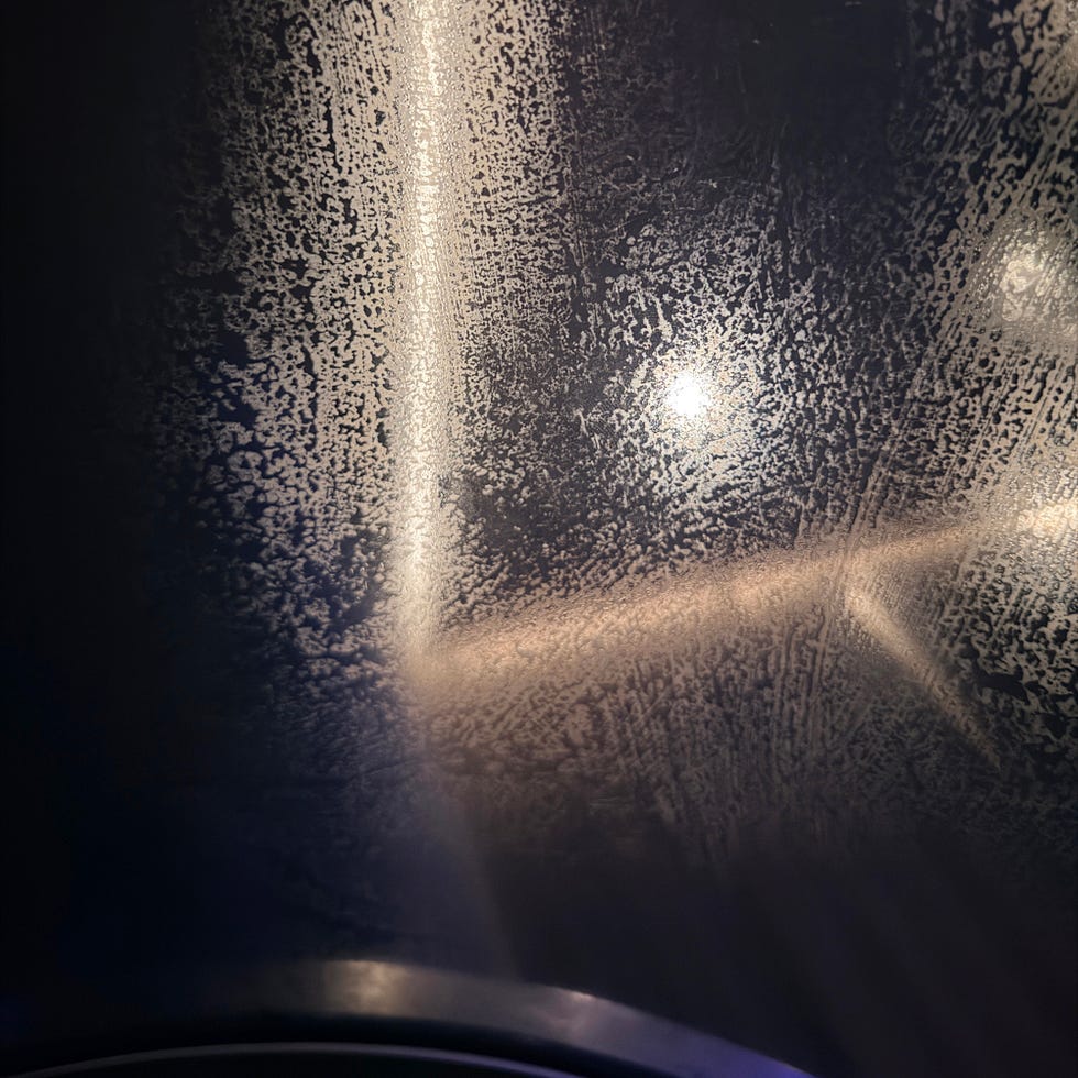 Condensation forming patterns on a glass surface with faint light reflections in the background.