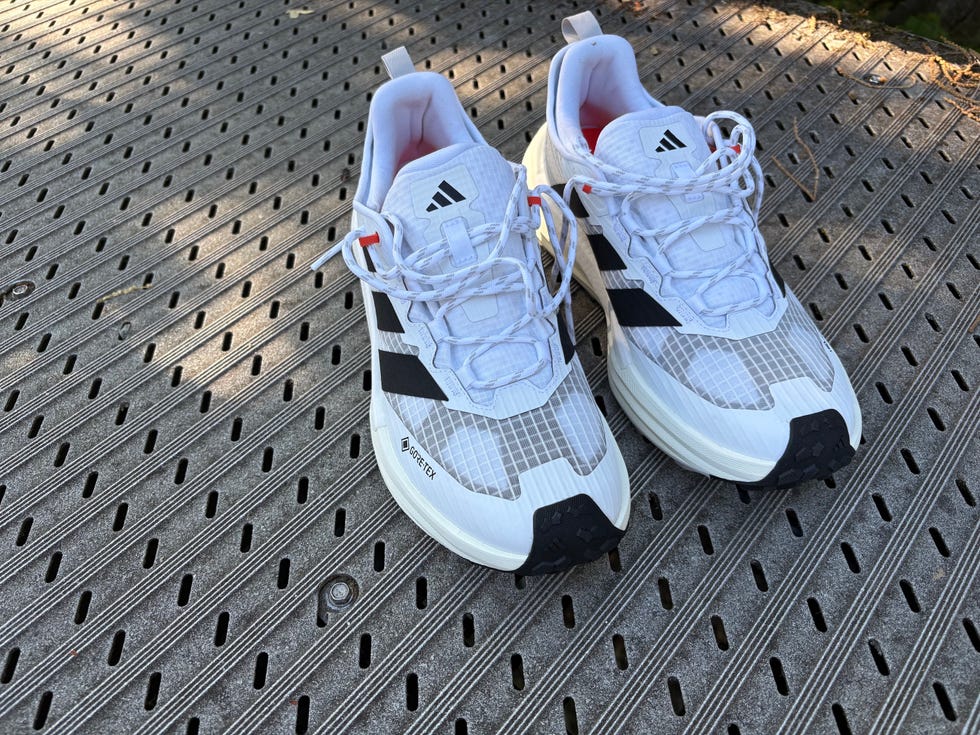 White and black Adidas running shoes positioned on a textured surface.