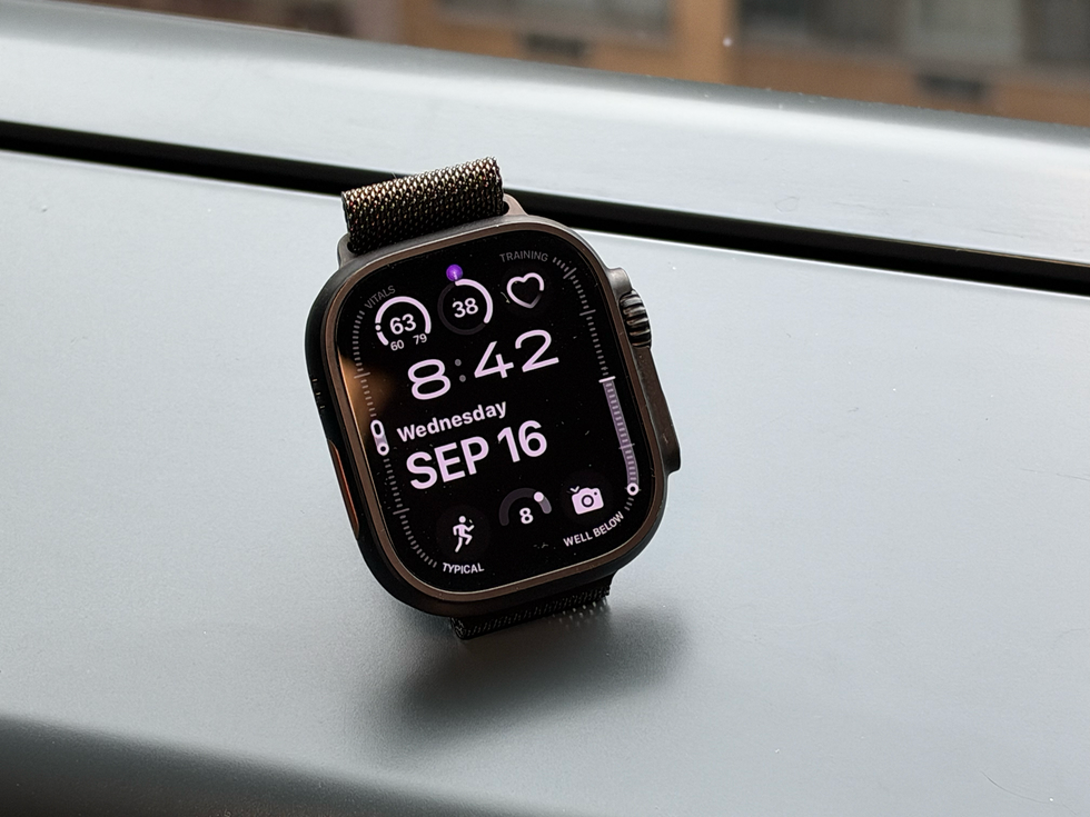Smartwatch displaying time, date, and health metrics on a grey surface.