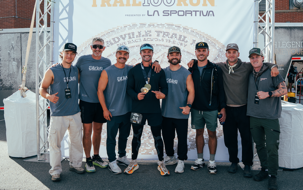 Group of participants celebrating at the Leadville Trail 100 Run event with a backdrop and medals.